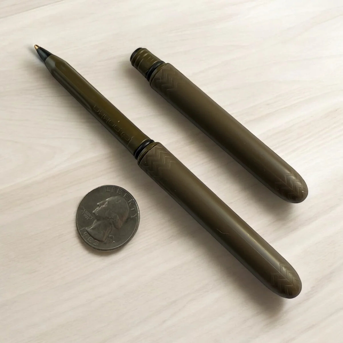 Earth brown Pokka Pocket Pen beside a quarter for size comparison