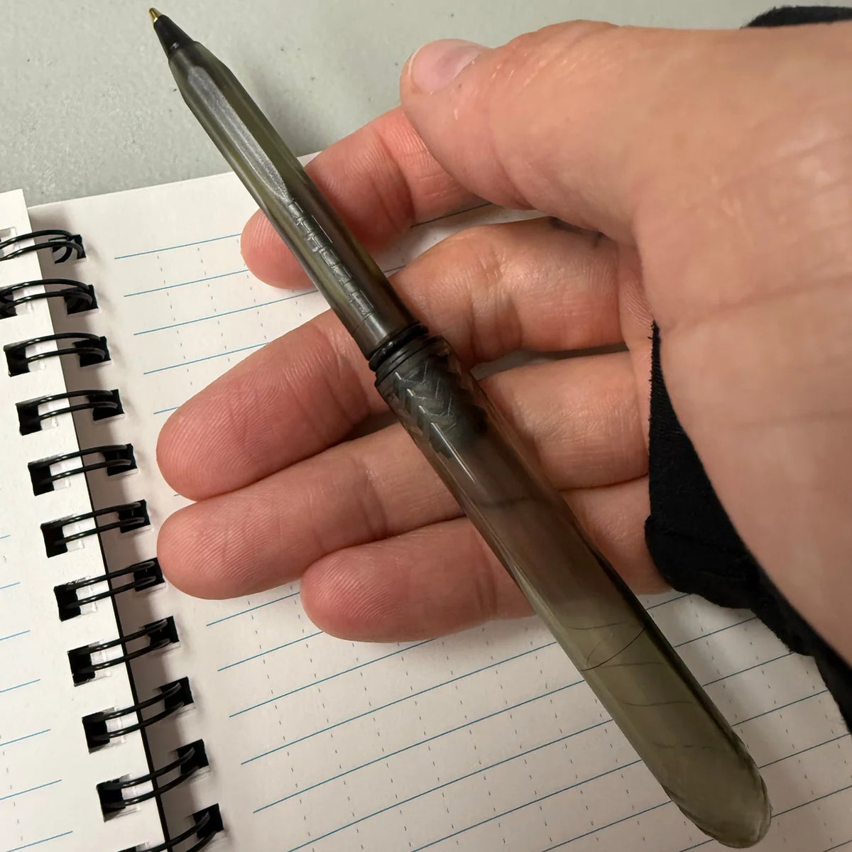 Onyx translucent black Pokka Pocket Pen held above a spiral notebook